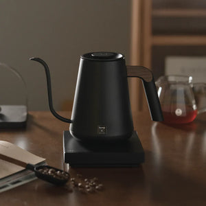 Black electric kettle with narrow spout and wooden handle for barista and brew accessories from Timemore, all about coffee.