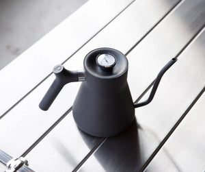 Matte black kettle with a narrow gooseneck and built-in thermometer, brewing accessory, all about coffee.