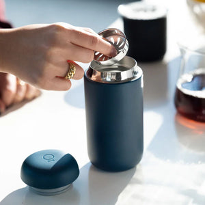 Hand inserting filter into matte blue reusable coffee cup, part of Take away and EspressoGear, all about coffee.
