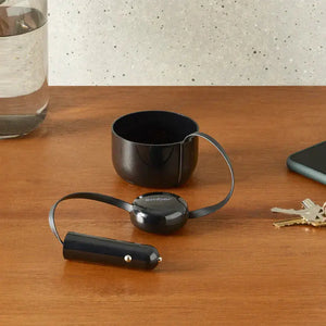 Car charger for Ember electric mug placed on wooden table with car adapter and reflection details.